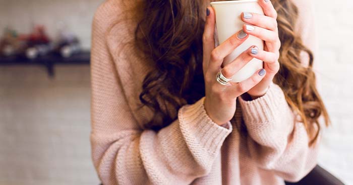 Image: A Woman In A Fashionable Sweater Holds A Cup Of Coffee.