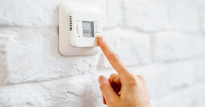 Image: A Person Adjusting A Thermostat.