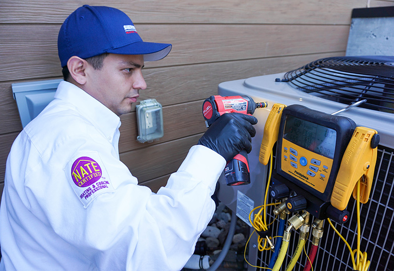 NATE-certified Sierra Air technician checking system pressures on an outdoor unit at a Reno home