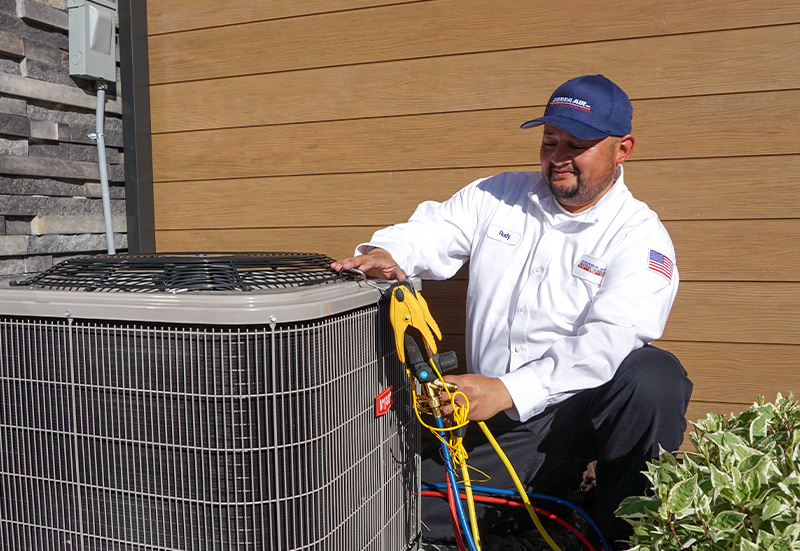 Sierra Air technician inspecting an outdoor AC condenser beside a Reno home